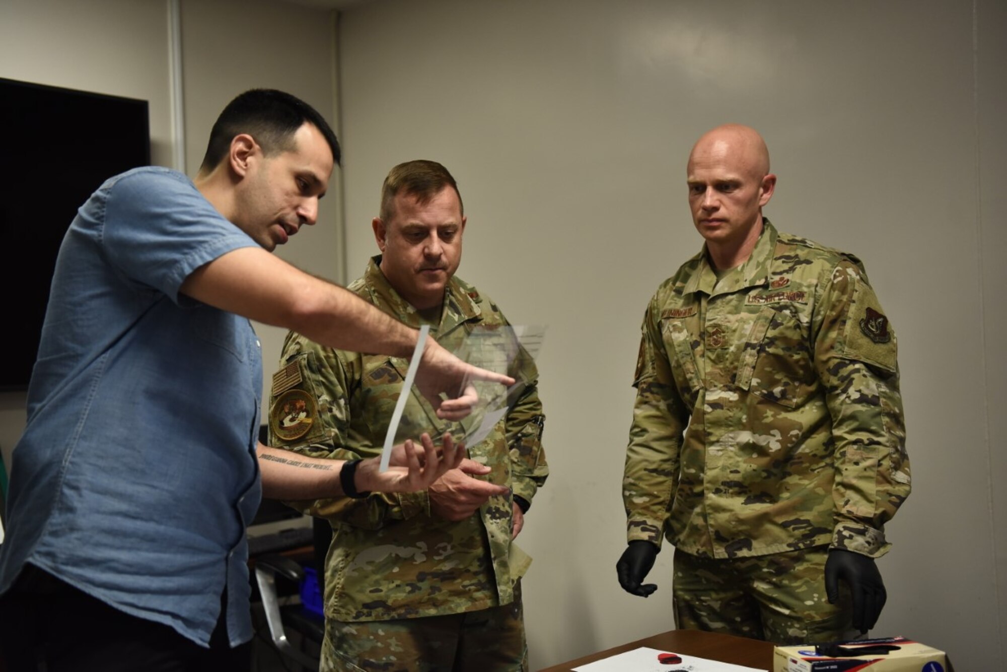 A special agent points at a clear file to two military members.