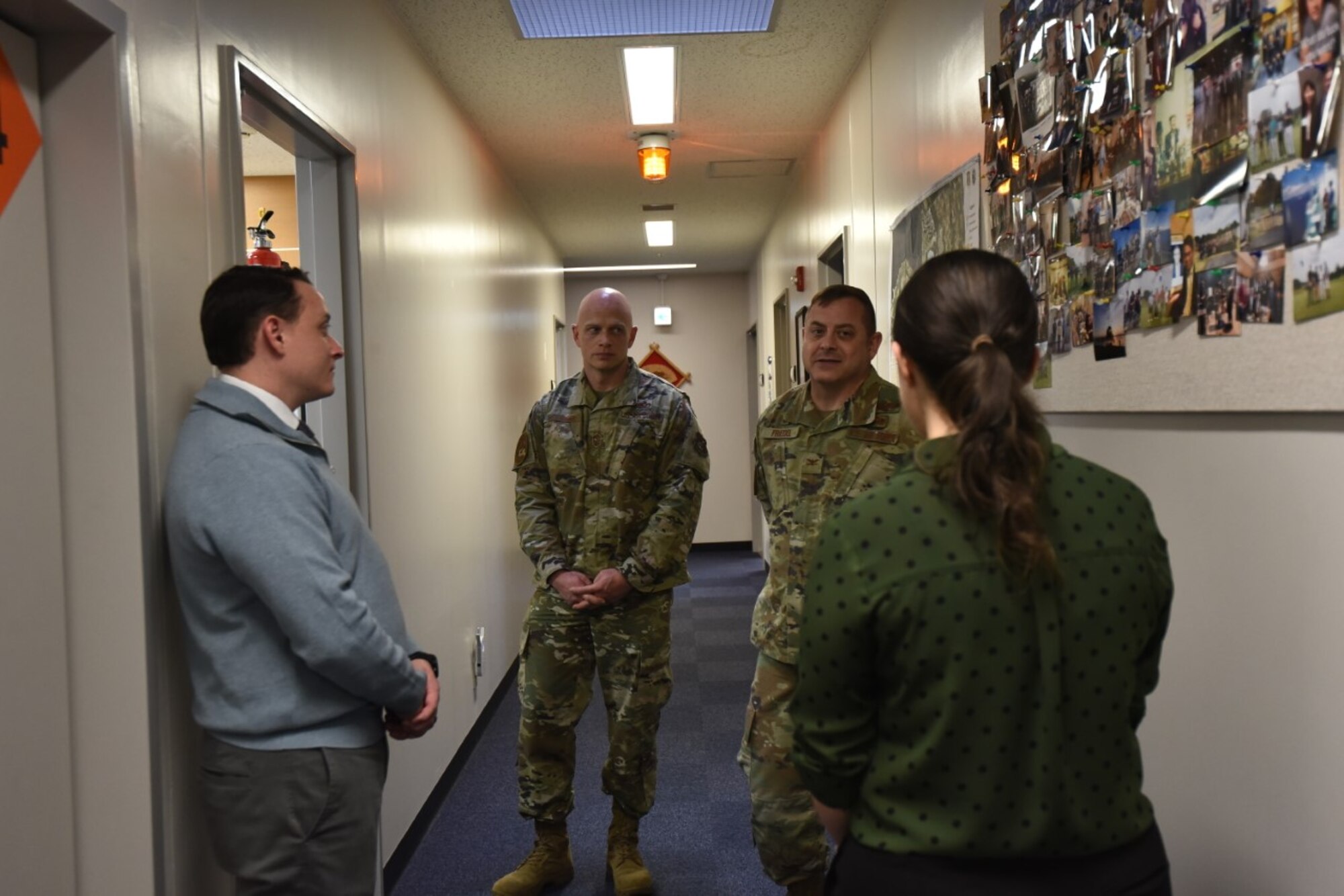Two military members talk to a lady in a hallway