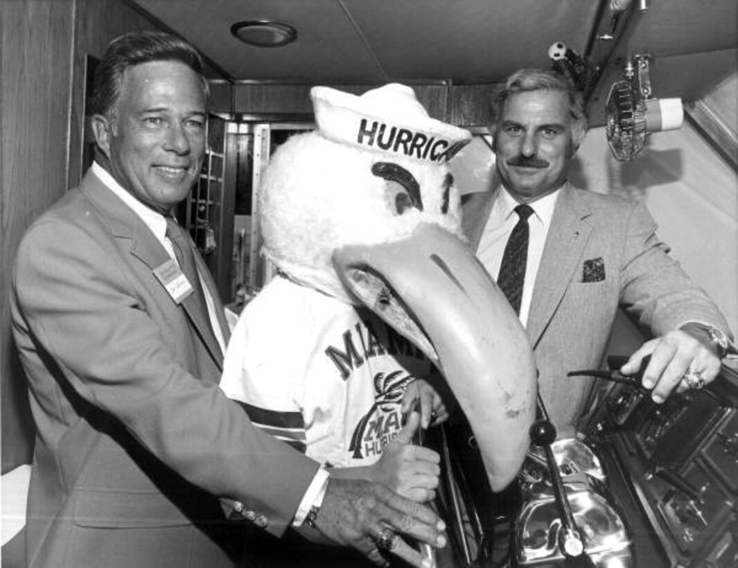 Men smile at a large football mascot.