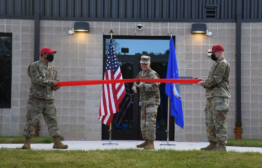 Col. Tyler Schaff, 316th Wing and installation commander, cuts a ribbon to signify the opening of the new Combat Arms Training and Maintenance facility at Joint Base Andrews, Md., Nov. 1, 2021. The new facility features many upgrades from the previous building, including a new 21-position firing range, weapons and range equipment maintenance area and office and common spaces for the instructors. (U.S. Air Force photo by Senior Airman Spencer Slocum)