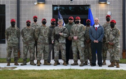 Col. Tyler Schaff (center), 316th Wing and installation commander, and Combat Arms Training and Maintenance staff pose for a group photo following the opening of their new facility at Joint Base Andrews, Md., Nov. 1, 2021. Instructors now have the capability to completely control lighting inside the range, which allows for live night-fire firing operations at any time of day. (U.S. Air Force photo by Senior Airman Spencer Slocum)