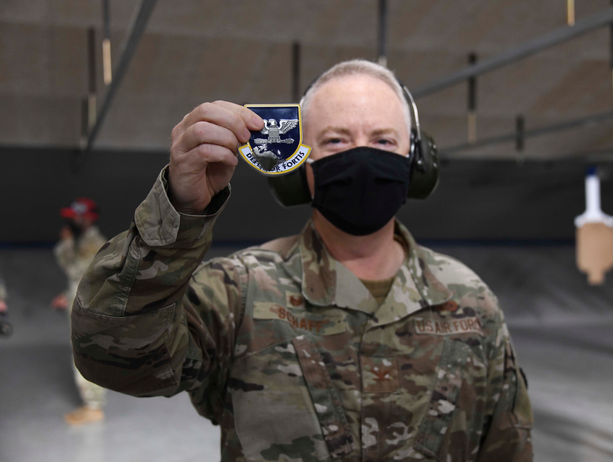 Col. Tyler Schaff, 316th Wing and installation commander, holds up a challenge coin at the new Combat Arms Training and Maintenance facility, Joint Base Andrews, Md., Nov. 1, 2021. The coin was placed on a target for Schaff to shoot in honor of the CATM’s opening (U.S. Air Force photo by Senior Airman Spencer Slocum)