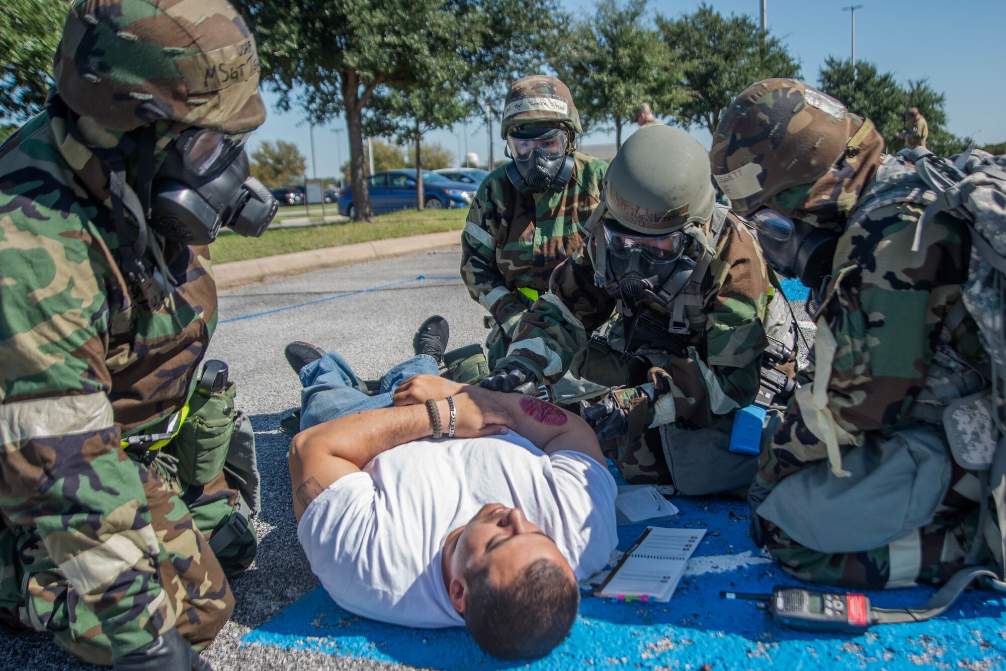 Airmen in exercise gear simulate performing self-aid and buddy care