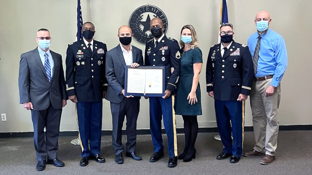 a group of people pose holding a certificate