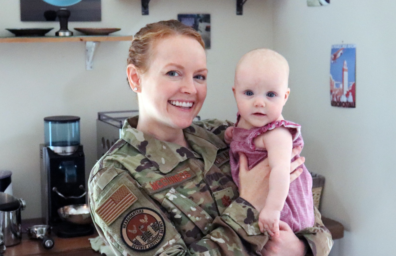 Woman in Air Force camo uniform holds her baby daughter.