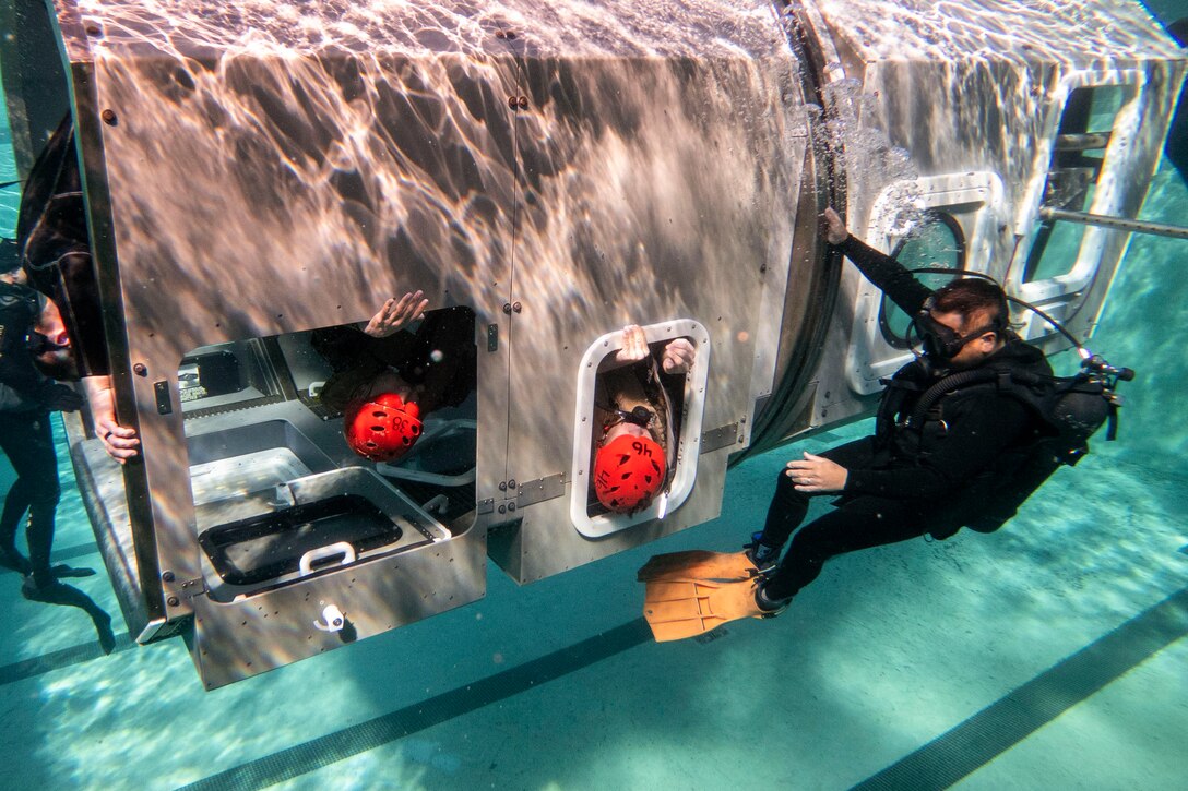 Marines exit a vehicle while underwater.