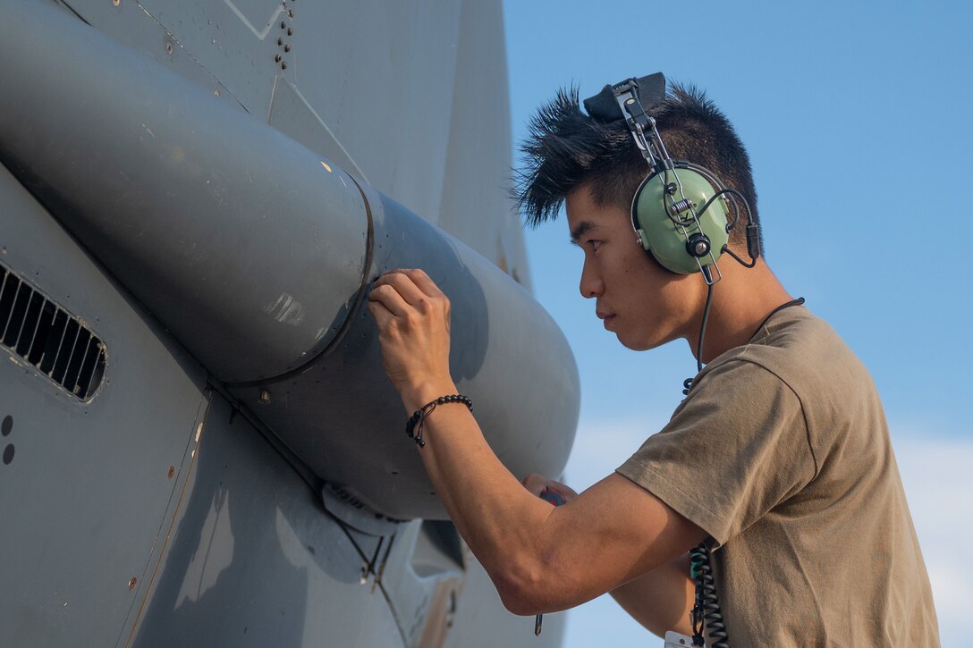 An airman tightens a bolt on an aircraft.