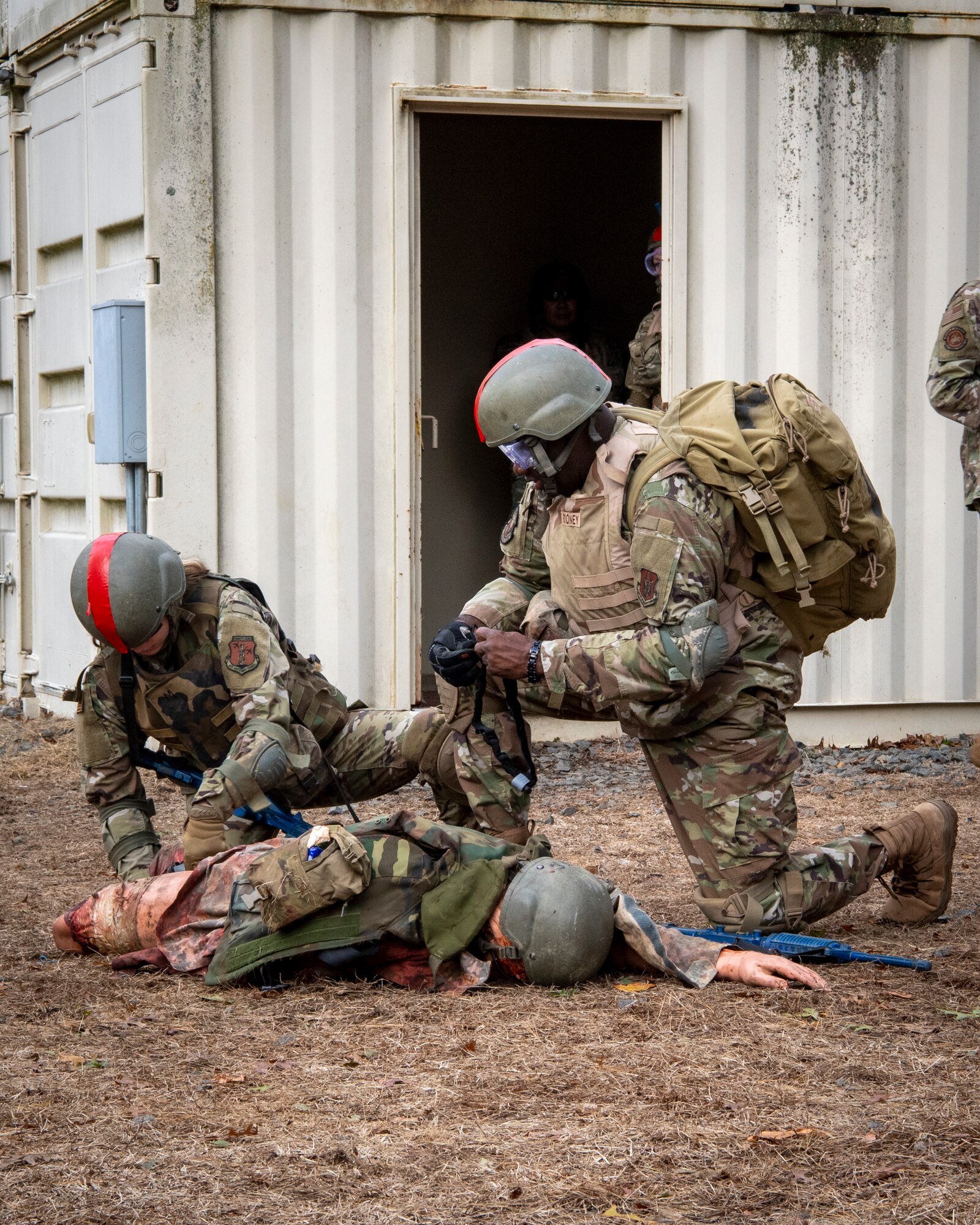 U.S. Air Force National Guardsman Senior Airman Katelynn McFall, 171st Air Refueling Wing, Pennsylvania, and Reserve Citizen Airman Technical Sgt. Kevin Hyde, 514th Aeromedical Staging Squadron, Joint Base McGuire-Dix-Lakehurst, New Jersey, simulate providing care under fire on an “injured comrade” during the mass casualty incident exercise of the Tactical Combat Casualty Care course at the Medical Simulation and Training Center at JB MDL, N.J., October 31, 2021. True to the concept of Air Force Total Force Integration, reserve, guard, and active duty squadrons came together to participate in this potentially life-saving course.
