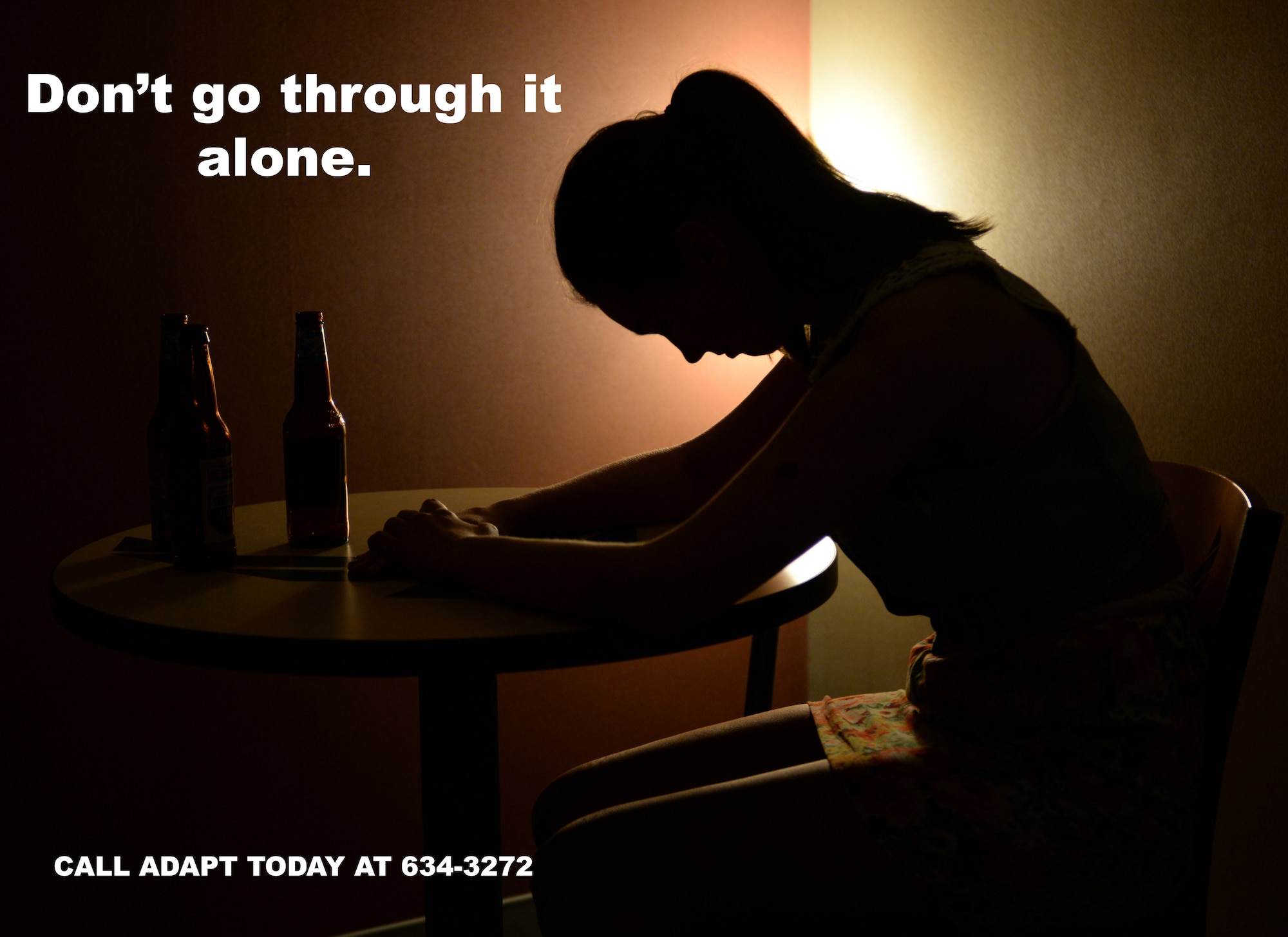 A girl sitting at a table with bottles.