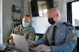 Maj. Victor Yartz, left, Pennsylvania National Guard, and Sgt. Craig Polen, Pennsylvania State Police Bureau of Communications Information Services, work together at the FEMA Region 3-facilitated Fall Regional Emergency Communications Coordination Working Group at Fort Indiantown Gap, Pennsylvania, on Nov. 3, 2021. Pennsylvania State Police set-up their mobile command center at the event.
