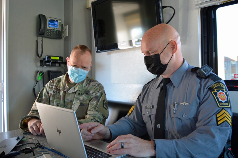 Maj. Victor Yartz, left, Pennsylvania National Guard, and Sgt. Craig Polen, Pennsylvania State Police Bureau of Communications Information Services, work together at the FEMA Region 3-facilitated Fall Regional Emergency Communications Coordination Working Group at Fort Indiantown Gap, Pennsylvania, on Nov. 3, 2021. Pennsylvania State Police set-up their mobile command center at the event.