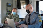 Maj. Victor Yartz, left, Pennsylvania National Guard, and Sgt. Craig Polen, Pennsylvania State Police Bureau of Communications Information Services, work at the FEMA Region 3-facilitated Fall Regional Emergency Communications Coordination Working Group at Fort Indiantown Gap, Pennsylvania, Nov. 3, 2021. Pennsylvania State Police set-up their mobile command center at the event.
