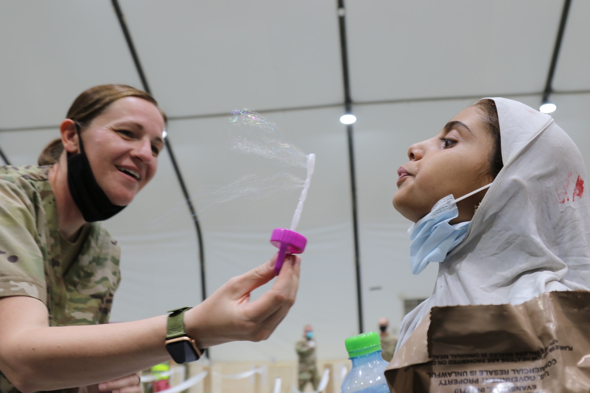 An Afghan child blows bubbles with Capt. Tiffany Hendershot's help during Operation Allies Refuge in Kuwait. As an Army behavioral therapist, Hendershot said she wanted to help the children because she knows how childhood trauma, such as what they experienced, can lead to behavioral issues later on. (U.S. Army photo by 1st Lt. James Mason)