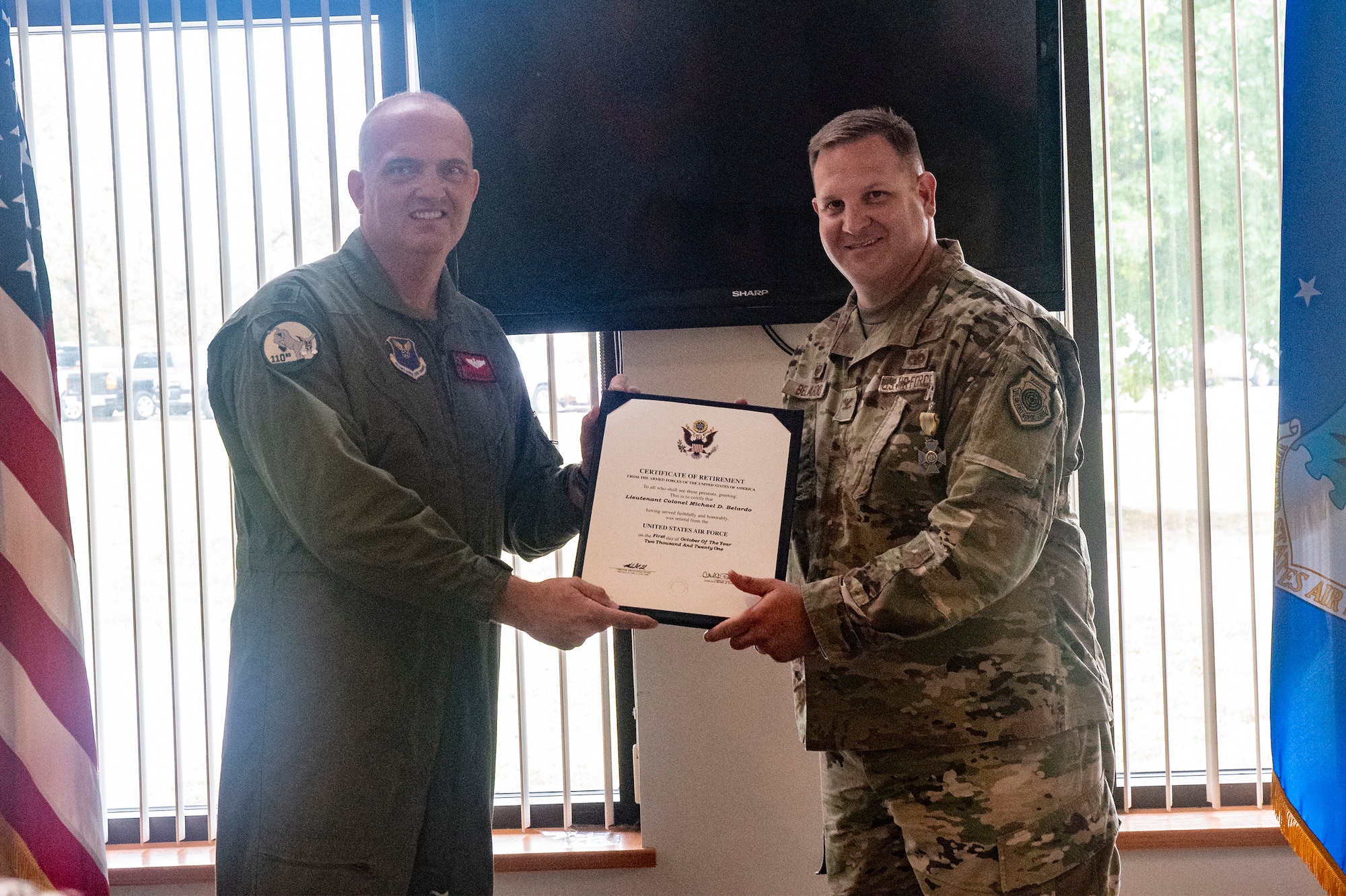 Retired Lt. Col. Ryan Bailey, former 131st Bomb Wing pilot, presents Col. Michael Belardo with a certificate f retirement during his retirement ceremony Oct. 2, 2021, at Whiteman Air Force Base, Missouri. Belardo, a B-2 Spirit stealth bomber pilot and 131st Maintenance Group commander, retired after many years of service in the Missouri Air National Guard. (U.S. Air National Guard photo by Master Sgt. John E. Hillier)