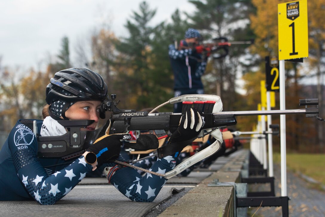 A soldier fires a weapon while laying on the ground.