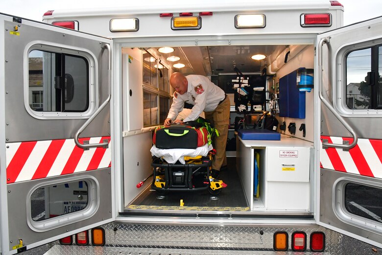 Joshua Mork moves equipment around inside the back of an ambulance.