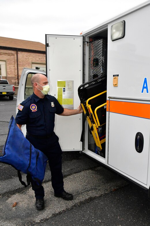 Bert Linford remove equipment from a side door on the back of an ambulance.
