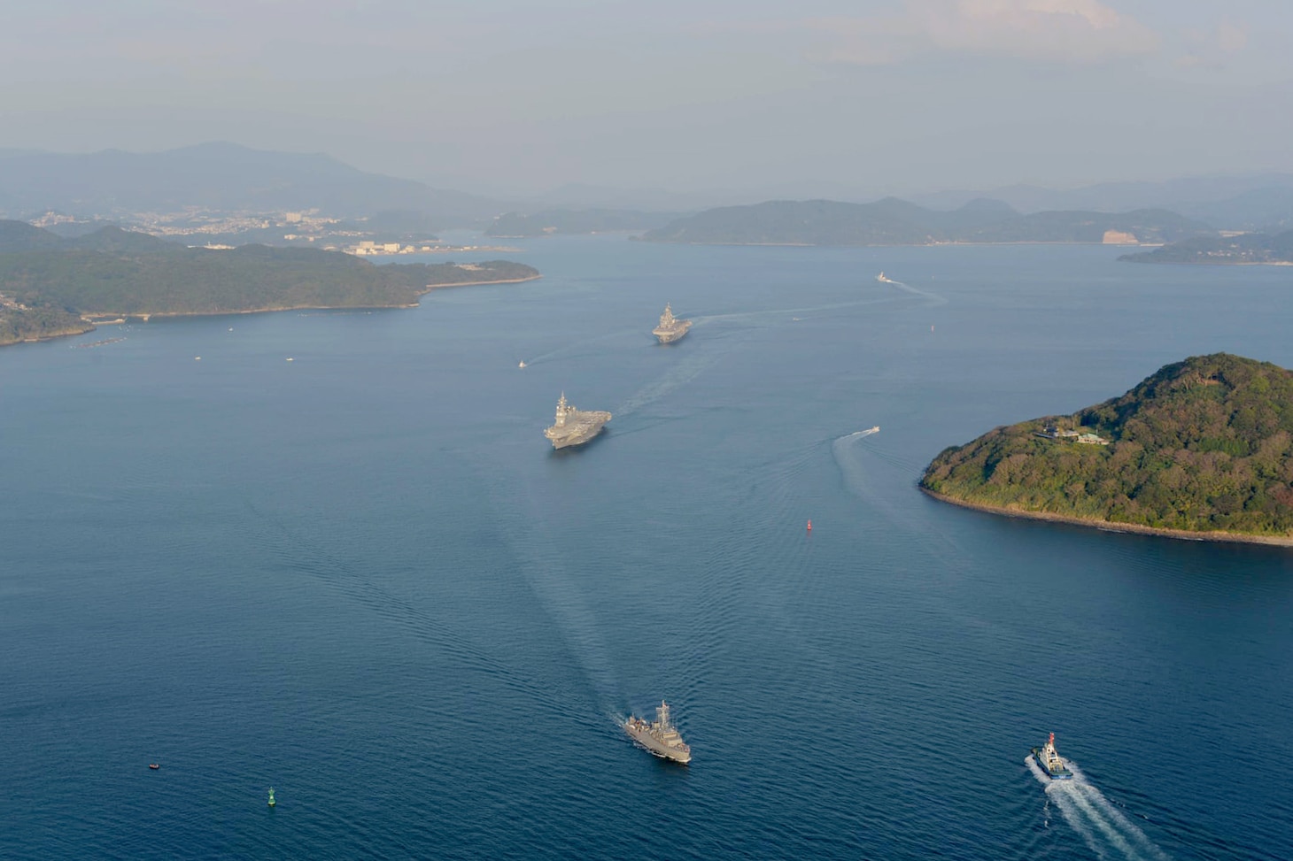 SASEBO, Japan (Nov. 3, 2021) Japan Maritime Self-Defense Force (JMSDF) helicopter destroyer JS Ise (DDH 182) and the U.S. Navy's forward-deployed amphibious assault ship USS America (LHA 6), center, sail together departing Sasebo for integrated training with locally-based JMSDF ships. (JMSDF photo)