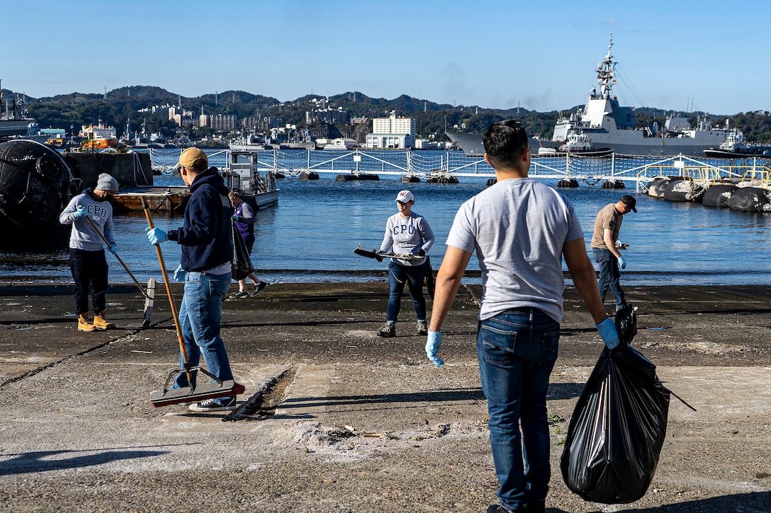 A group of people clean up a cement dock.