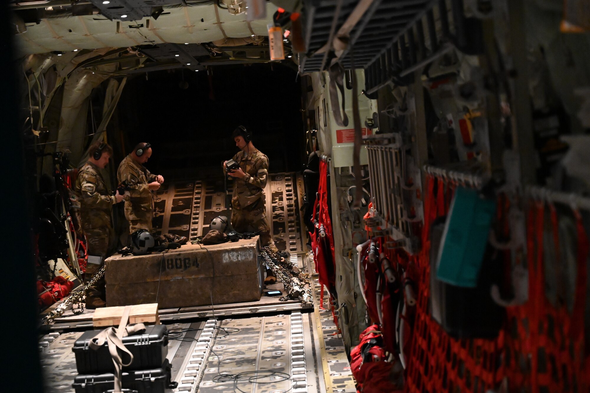 Loadmasters prepare gear in the back of a C-130J.