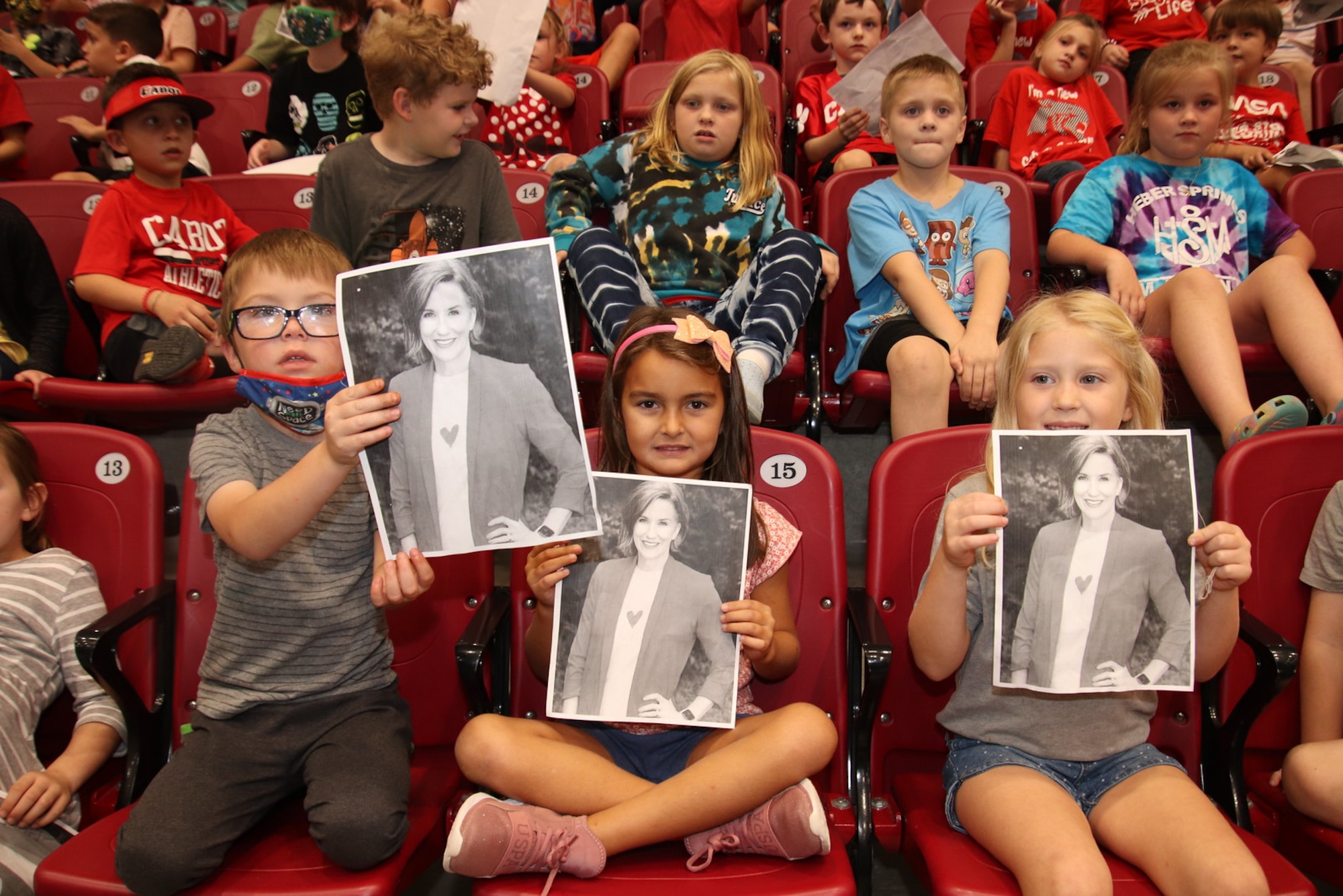 Students hold up photos of their teacher