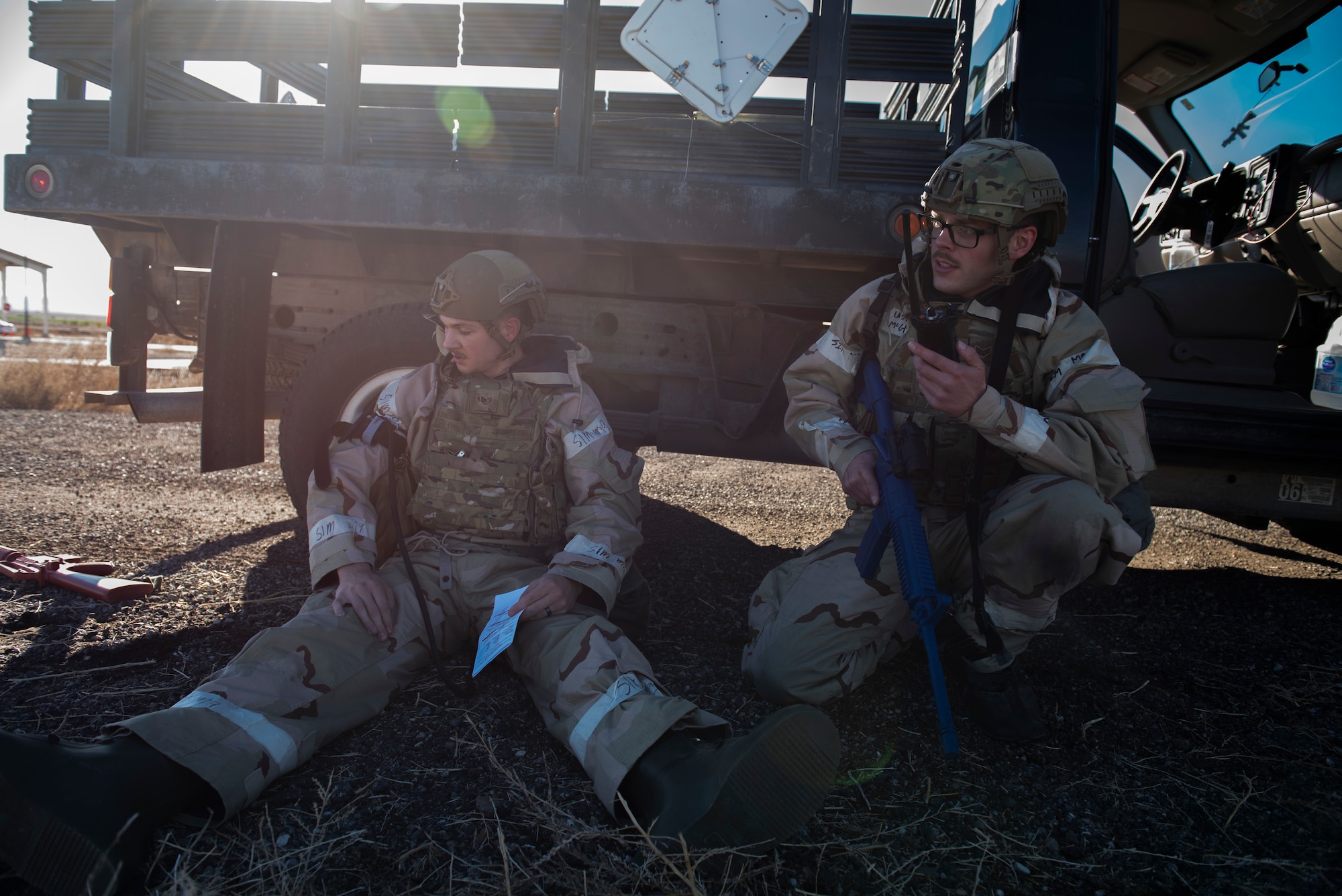 U.S. Air Force Staff Sgt. Dillon French, combat arms trainer, 366th Security Forces Squadron,(left) and Senior Airman Rick McGhee, combat arms trainer, 366th Security Forces Squadron, (right) take cover during a simulated ground attack on Mountain Home Air Force Base, Idaho, Oct. 28, 2021. During this exercise, Airmen responded to simulated chemical, biological, radiological, and nuclear explosive incidents; rehearsed self-aid and buddy care, and ran through other essential combat skills.