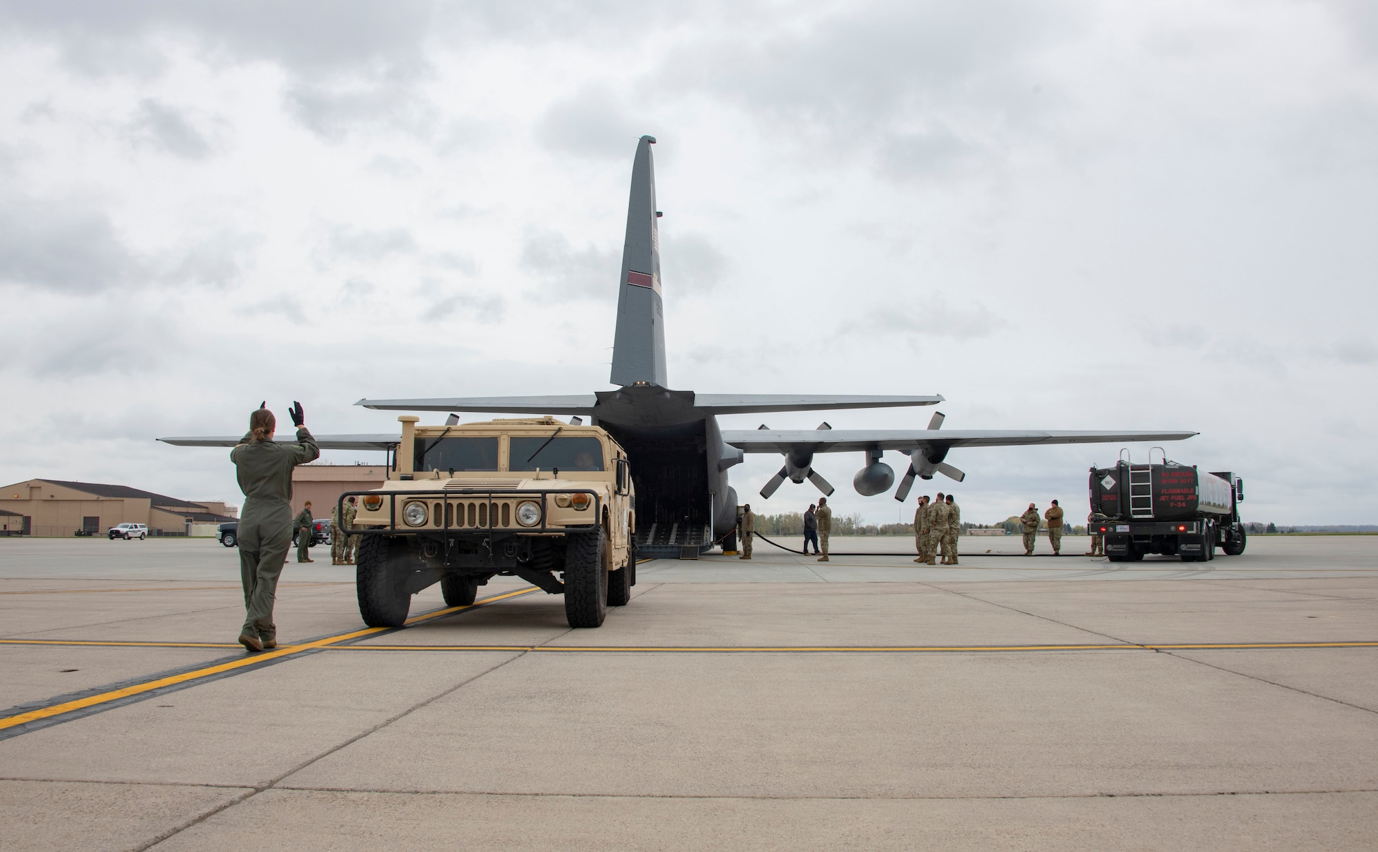 An Airman uses her arms to guide the Humvee driver safely onto the C-130