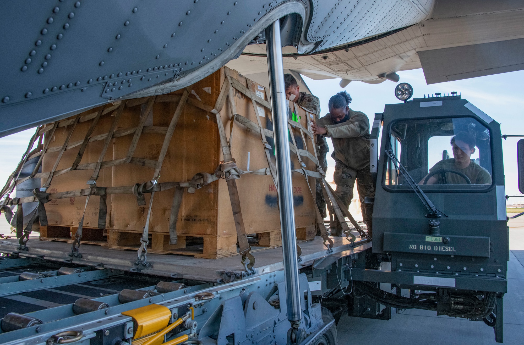 Airmen push a large pallet of cargo