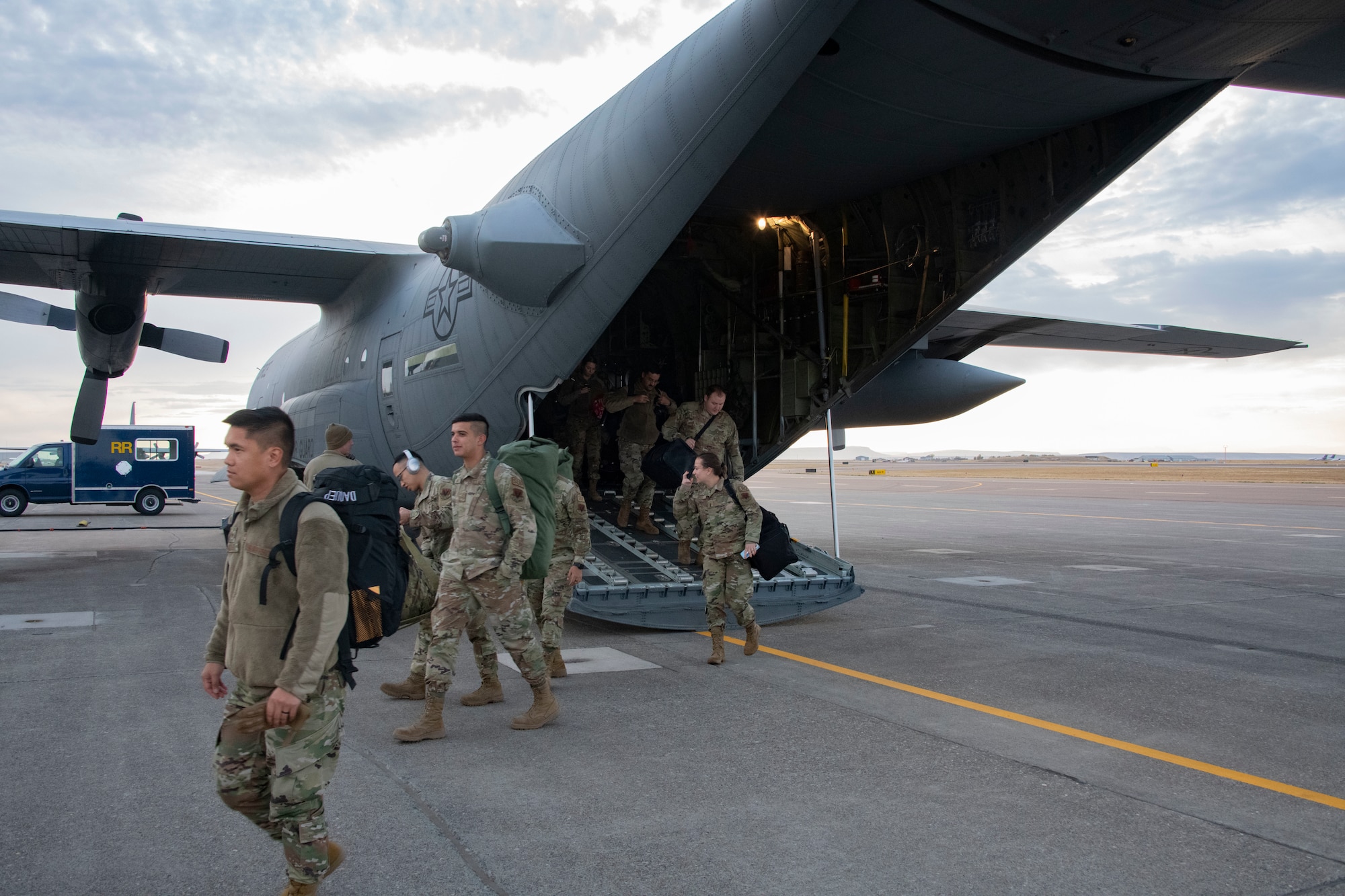 Airmen walk out the back of a C-130