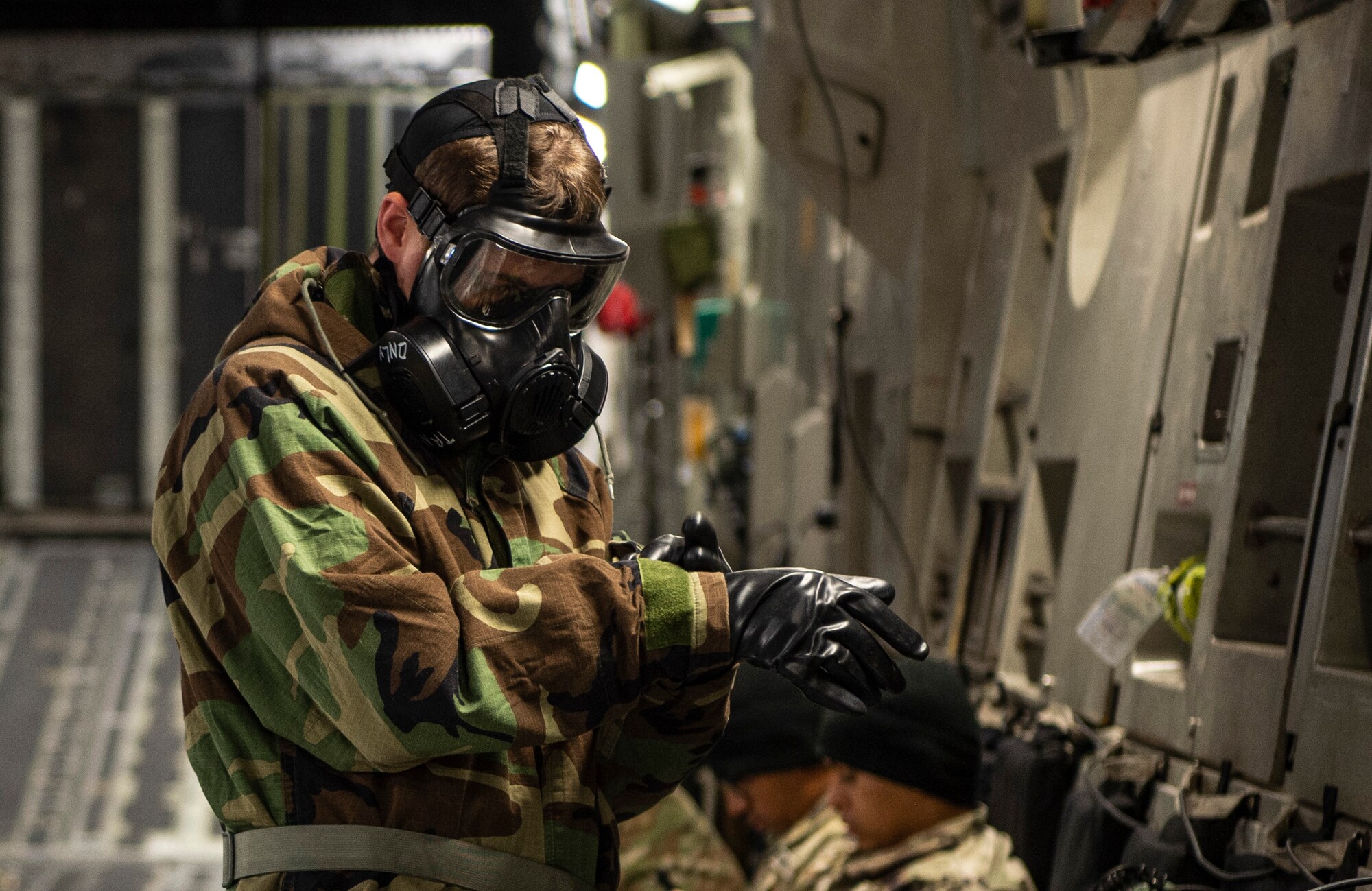 U.S. Air Force Senior Airman James Reed, 62nd Aircraft Maintenance Squadron maintainer, adjusts his Mission Oriented Protective Posture (MOPP) gear glove during Exercise Rainier War 21B at Joint Base Lewis-McChord, Washington, Nov. 3, 2021. The exercise is designed to demonstrate the wing’s ability to operate and survive while defeating challenges to the U.S. military advantage in all operating domains – air, land, sea and cyberspace. (U.S. Air Force photo by Staff Sgt. Tryphena Mayhugh)