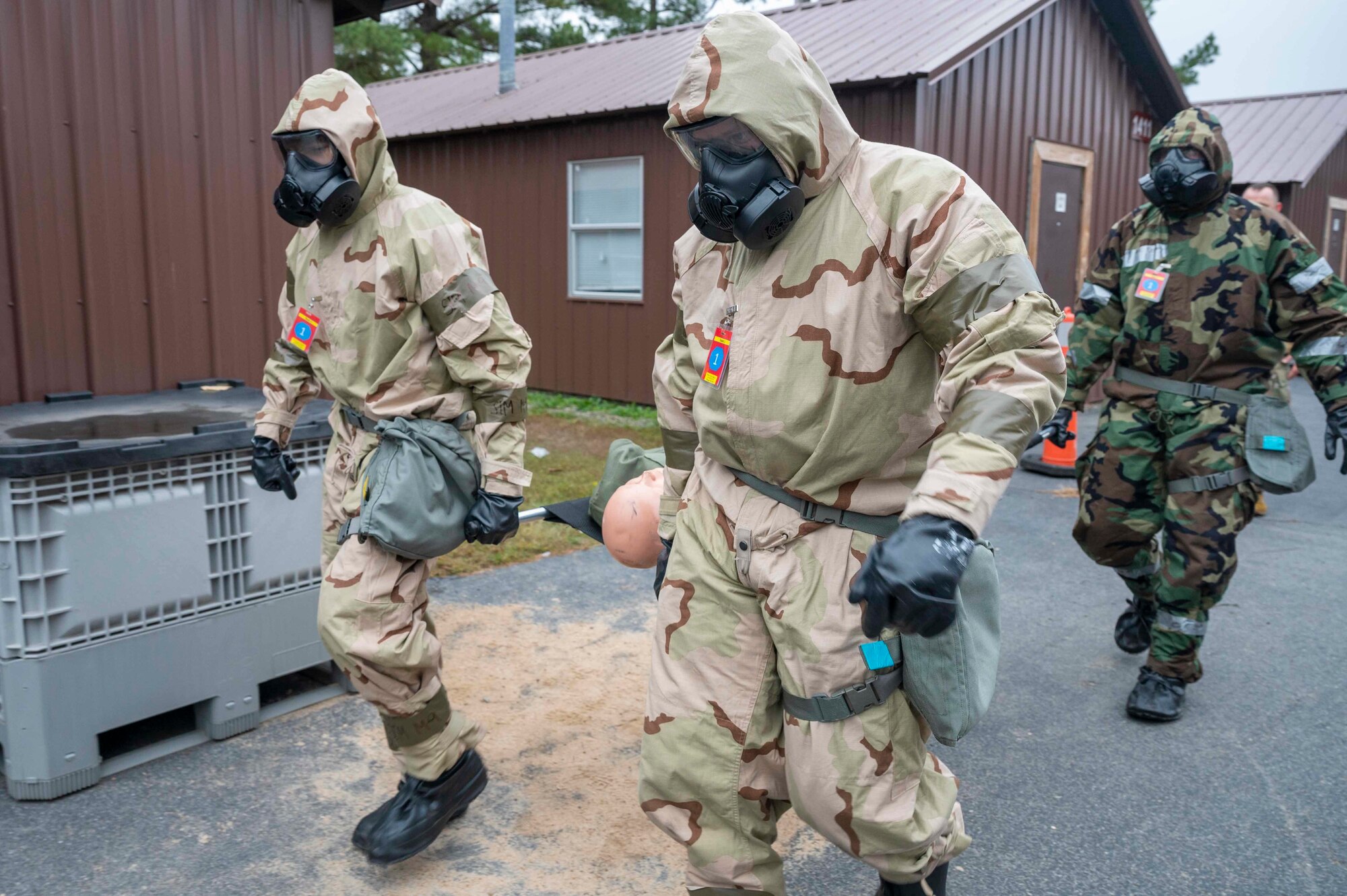 Airmen carry a dummie on a gurney during an exercise.