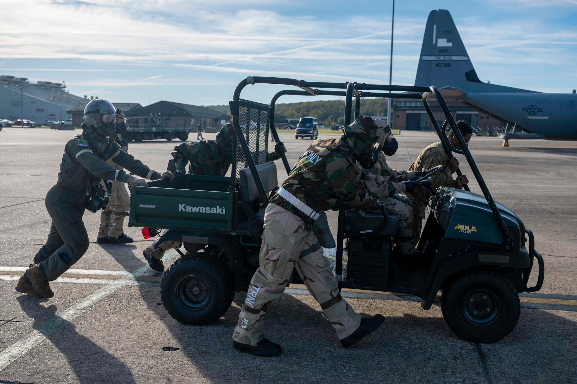 Airmen push a MULE to a C-130J