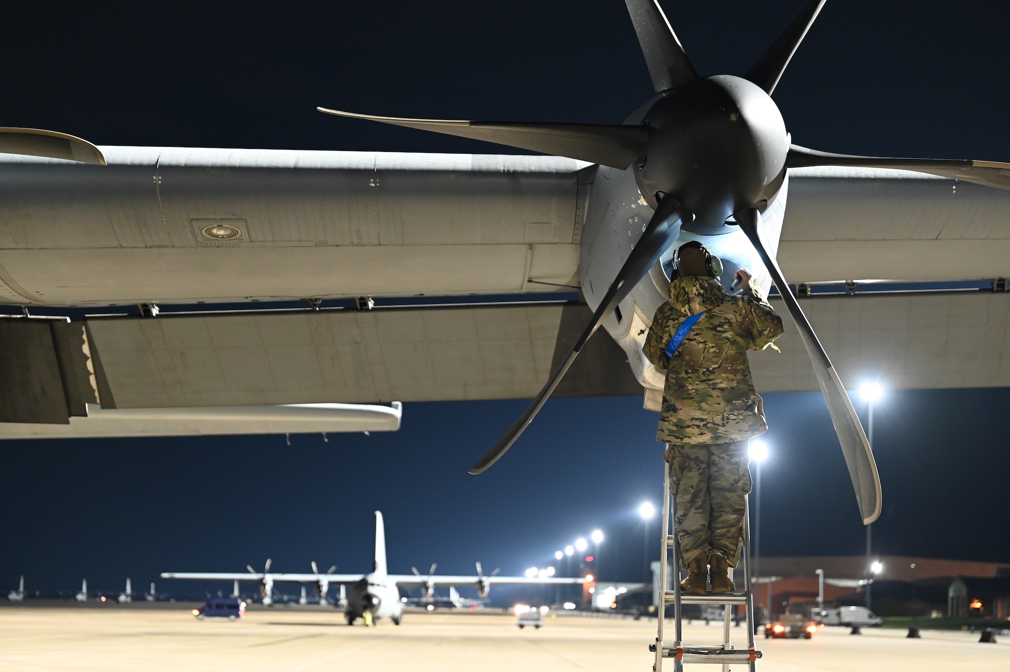 A maintenance airman works on a propeller on a C-130J.