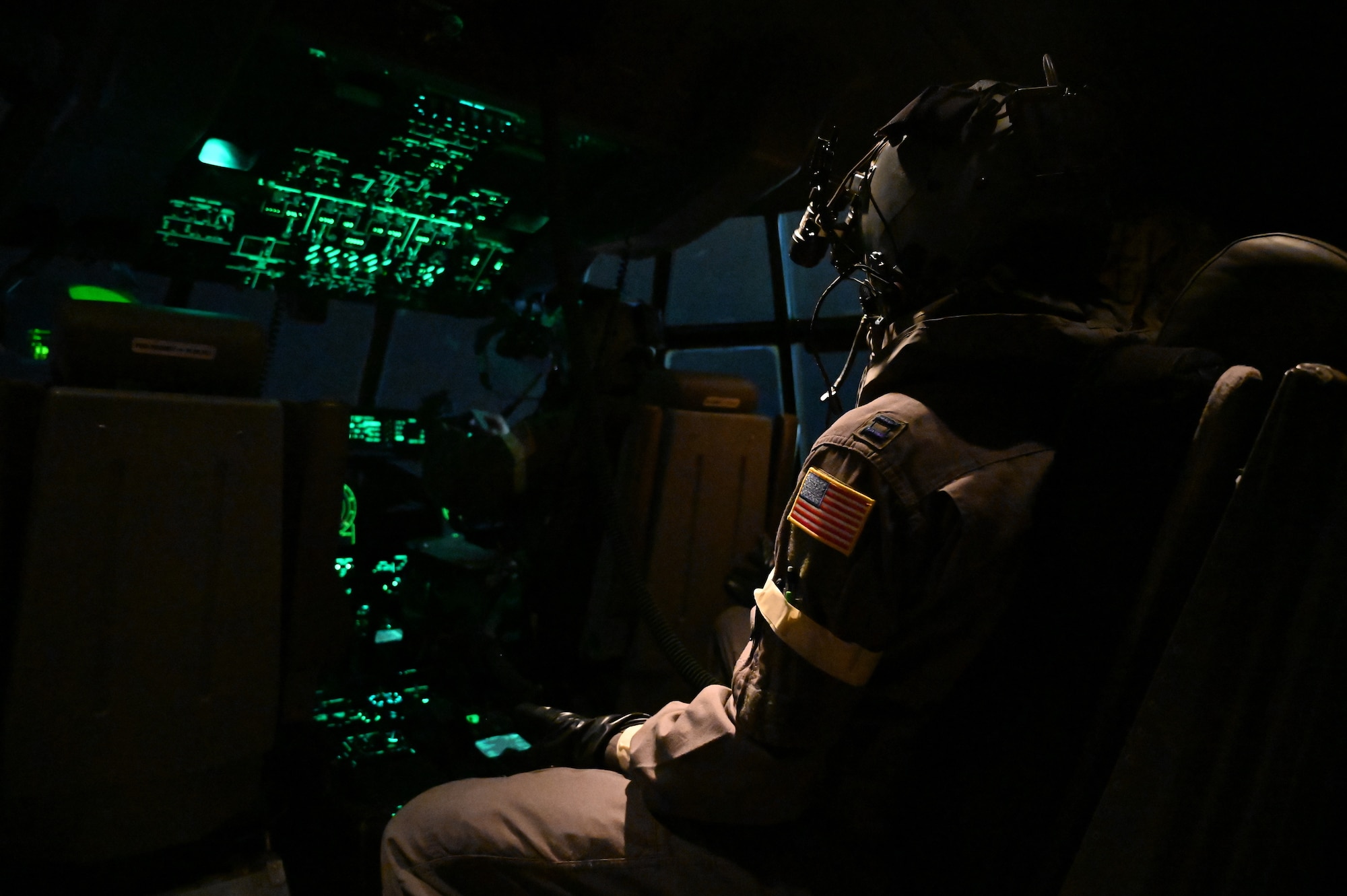 A pilot sits in the middle seat of a C-130J during a ROCKI exercise.