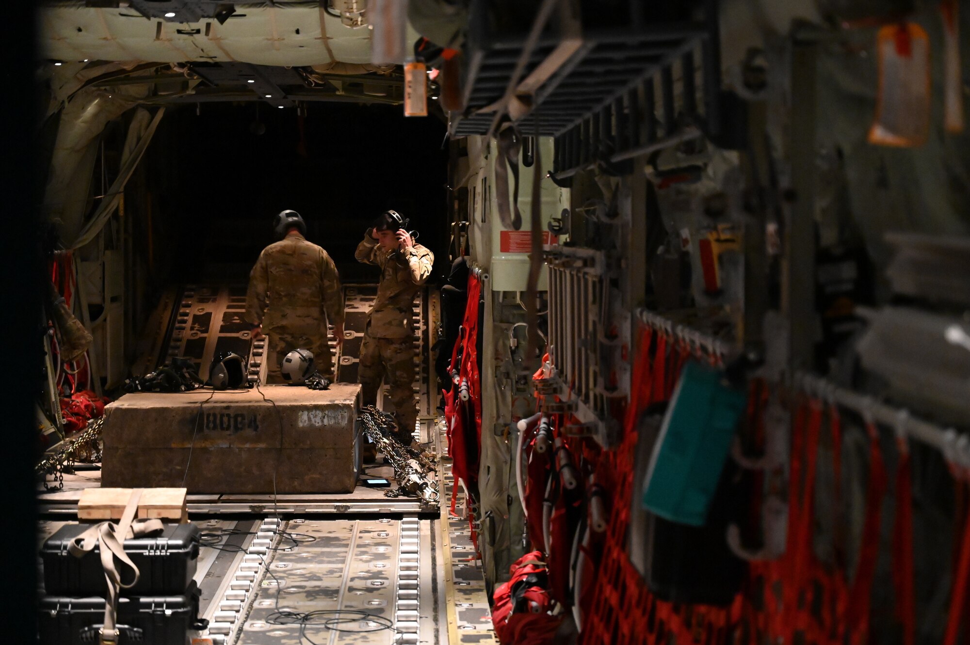 Loadmasters prepare gear in the back of a C-130J.