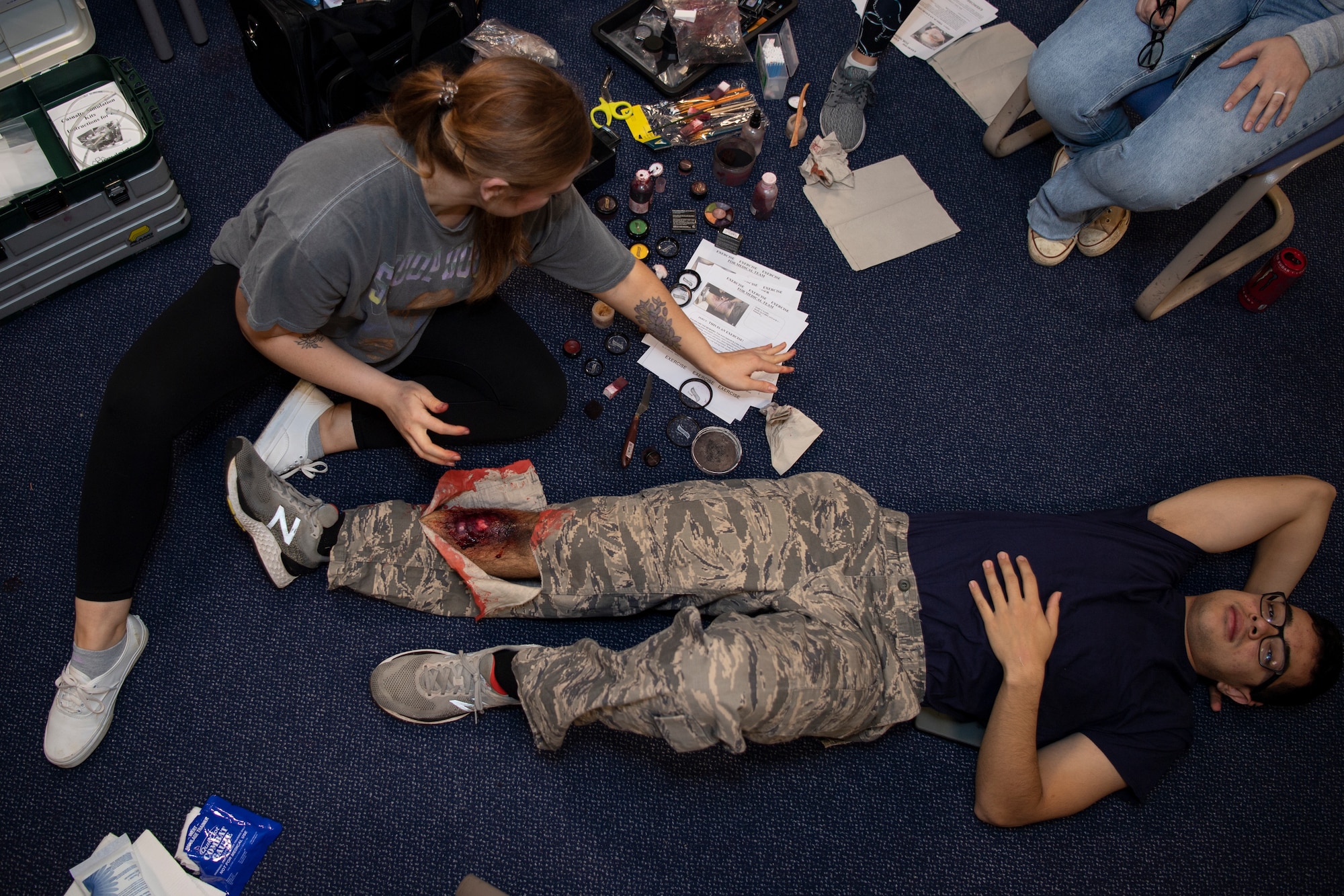 U.S. Air Force Senior Airman Alison Lewis, 52nd Medical Group public health technician, applies moulage to a simulated wounded victim’s leg during exercise Sabre Storm, Nov. 3, 2021, on Spangdahlem Air Base, Germany. During this simulated readiness exercise, the 52nd MDG was tested on mass casualty response, which consisted of 20 patients at once. (U.S. Air Force photo by Staff Sgt. Melody W. Howley)