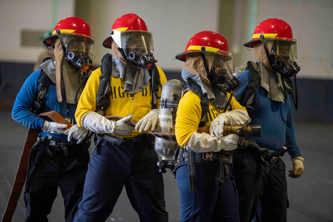 Sailors take part in a fire drill in the hangar bay during a fast cruise aboard the aircraft carrier USS Nimitz (CVN 68)