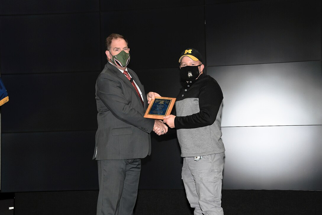 Man on left presenting an award to man on right.
