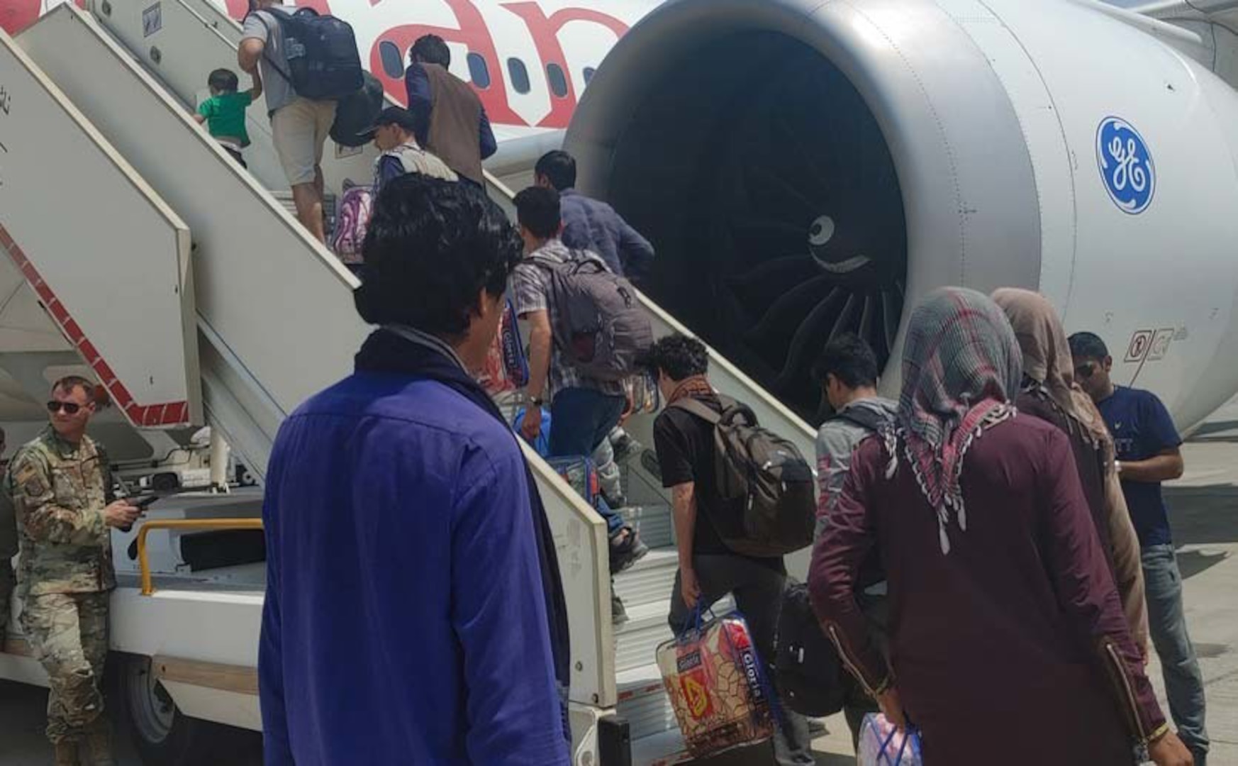 Afghan evacuees board a U.S.-chartered flight for their destination after a two-week stay in Kuwait, where they received medical screenings and were processed by Task Force Spartan personnel. Approximately 5,000 evacuees processed through Kuwait.