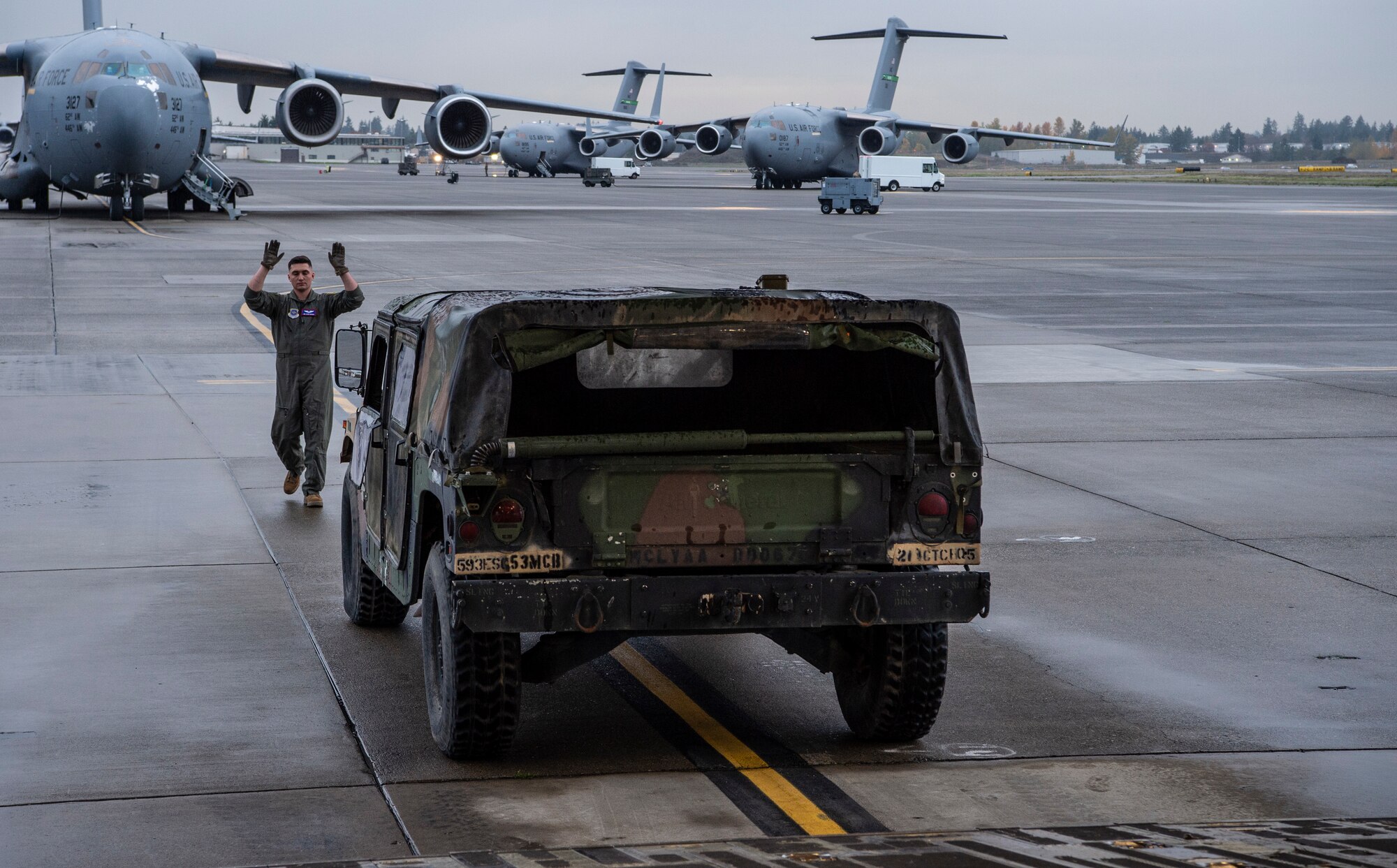 U.S. Air Force Senior Airman Peter Siviglia, 4th Airlift Squadron loadmaster, marshals a HUMVEE onto a C-17 Globemaster III during Exercise Rainier War 21B at Joint Base Lewis-McChord, Washington, Nov. 3, 2021. Rainier War 21B exercises and evaluates the wing’s ability to employ the force and their ability to perform during wartime and/or contingency taskings in a high-intensity, wartime contested, degraded and operationally limited environment while supporting the contingency operations against a near-peer adversary in the U.S. Indo-Pacific Command area of responsibility. (U.S. Air Force photo by Staff Sgt. Tryphena Mayhugh)