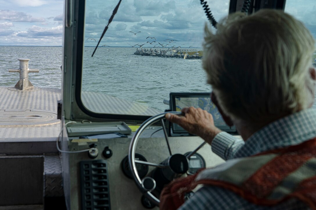 Jim Gunn, Coastal Design and Construction, Inc. Captain, and marine construction contractor, navigates the Chesapeake Bay towards a pelican pod during a multiagency tour of shoreline protection projects permitted  along sections of Rhodes Point, at Smith Island, Somerset County, Md., Oct. 7, 2021. The U.S. Army Corps of Engineers, Baltimore District’s Regulatory Program worked with project proponents to protect vulnerable sections of Chesapeake Bay coastline for a Hurricane Sandy Resiliency project post construct. Through the regulatory review process, USACE is responsible for evaluating coastal resilience actions that aim to protect the Nation’s aquatic resources through fair and balanced permitting decisions. (U.S. Army photo by Greg Nash)