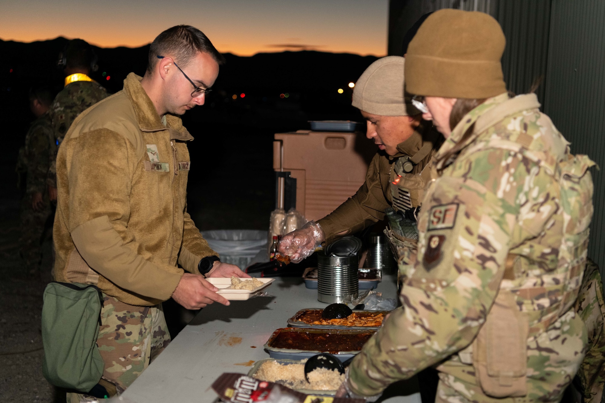 Two Airmen serve food to another Airman during Exercise Silent Arrow in Wendover Utah on October 27th 2021.