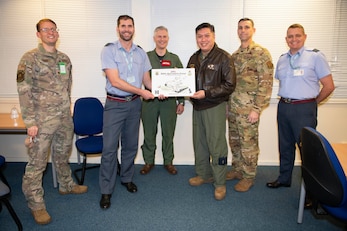 U.S. Air Force Col. Van Thai, center right, 100th Operations Group commander, presents a token of appreciation to the Royal Air Force Brize Norton command team for their contributions in working with the 100th Air Refueling Wing at RAF Brize Norton, England, Nov. 2, 2021. Airmen from the 100th Air Refueling Wing conducted operations out of RAFF as part of an Agile Combat Employment exercise. The operations taking place at Fairford provide a dynamic and partnership-focused training environment which ensures U.S. forces remain postured to deliver airpower across the European theater while strengthening interoperability with our NATO allies. (U.S. Air Force photo by Senior Airman Jennifer Zima)