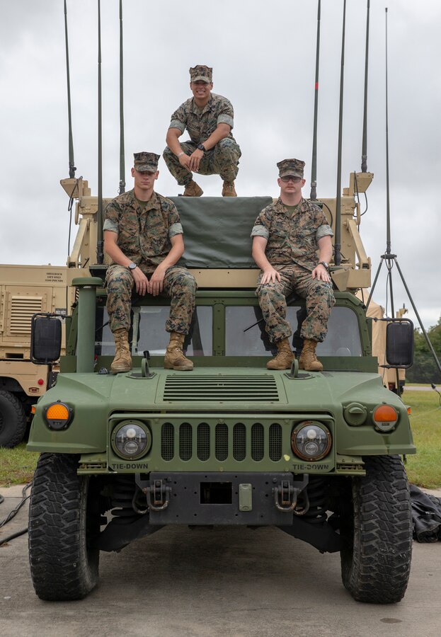 U.S. Marine Corps Cpl. Abraham A. Alvarado, top, Lance Cpl. Colton J. Schleder, left, and Lance Cpl. Jason I. Norr, right, pose on a CAC2S AN/MRQ-13 Communication Subsystem at Marine Corps Air Station Beaufort, South Carolina, Oct. 7, 2021. In March 2020, Alvarado identified a discrepancy with the equipment which prevented $1.6 million in damages, potential bodily injury and loss of life. (U.S. Marine Corps Photo by Lance Cpl. Kevin Lopez Herrera)