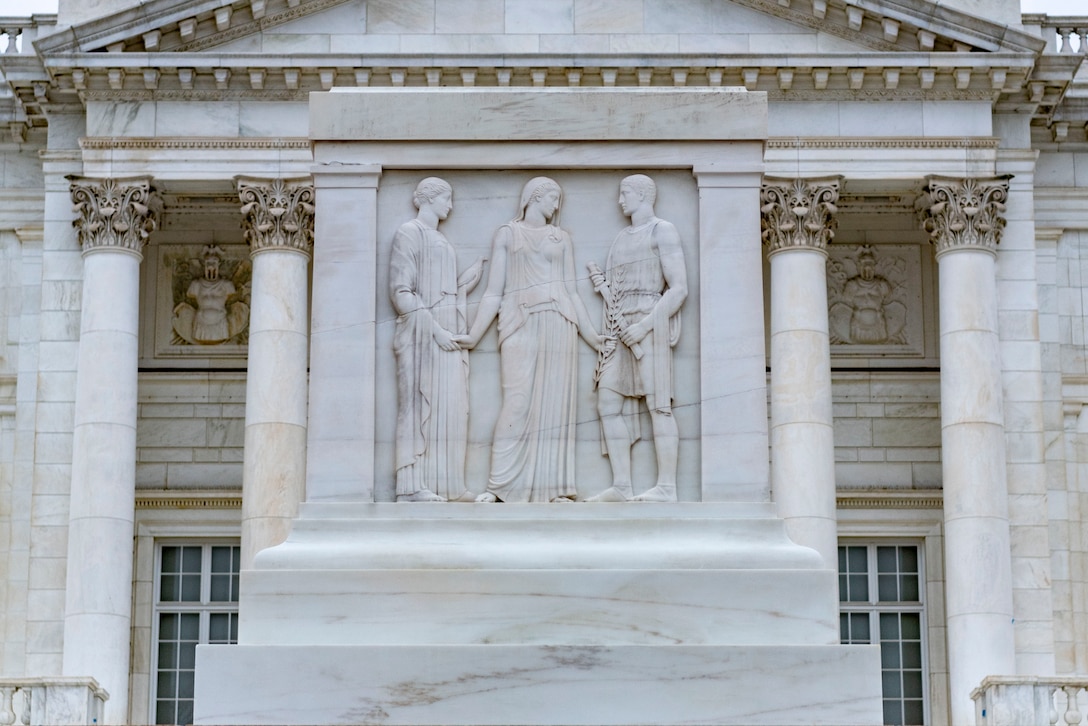 Three human figures adorn a marble tomb.