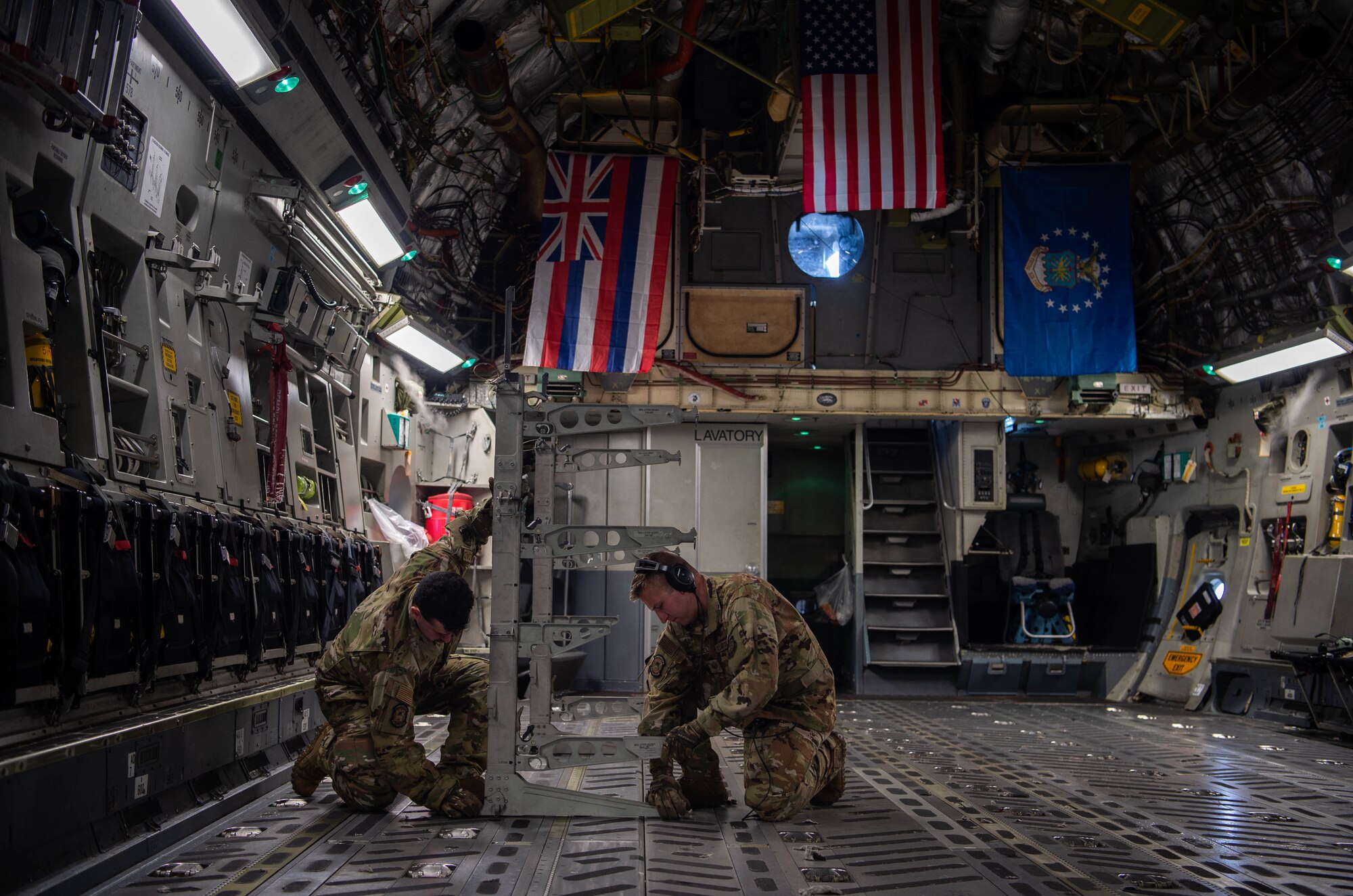 Tech. Sgt. Todd Hanggeli, 6th Airlift Squadron instructor loadmaster, and Airman 1st Class Thomas Dodd, 6th AS loadmaster, stage a litter stanchion while flying on a C-17 Globemaster III during the 535th Airlift Squadron’s training week around the Hawaiian Islands, Nov. 3, 2021. A litter stanchion is utilized by aircrew and aeromedical evacuation Airmen, providing stations to care for patients and evacuees. (U.S. Air Force photo by Senior Airman Alan Ricker)