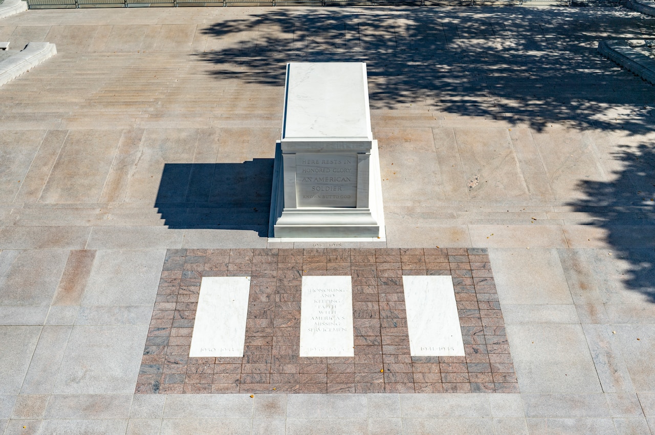 A tomb and three in-ground crypts on a plaza.