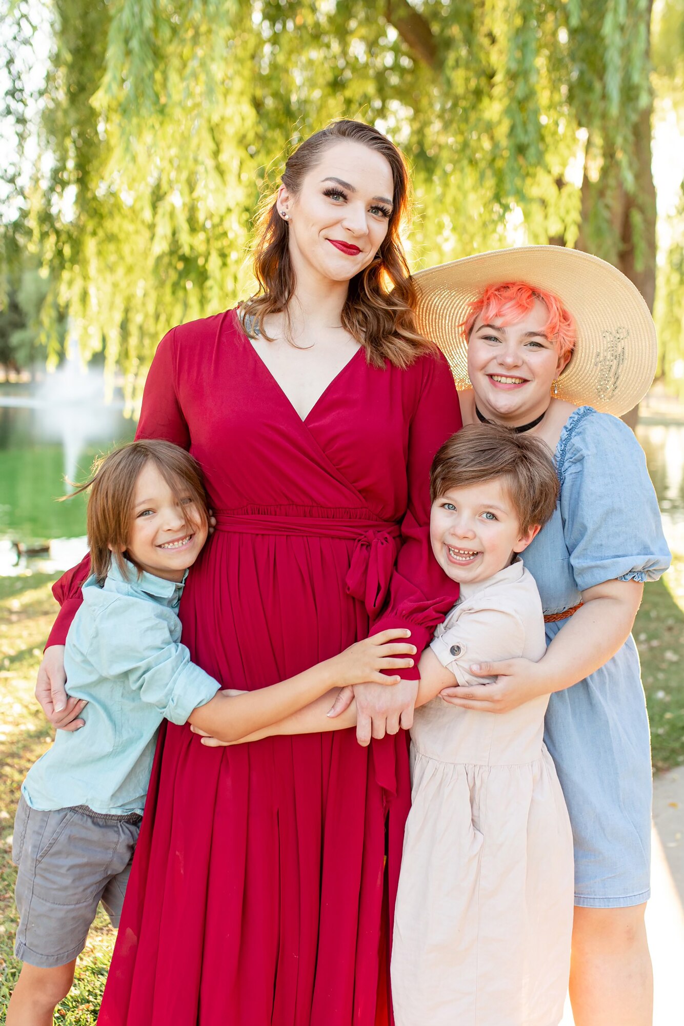 A woman in a red dress poses with her children for a family photo.