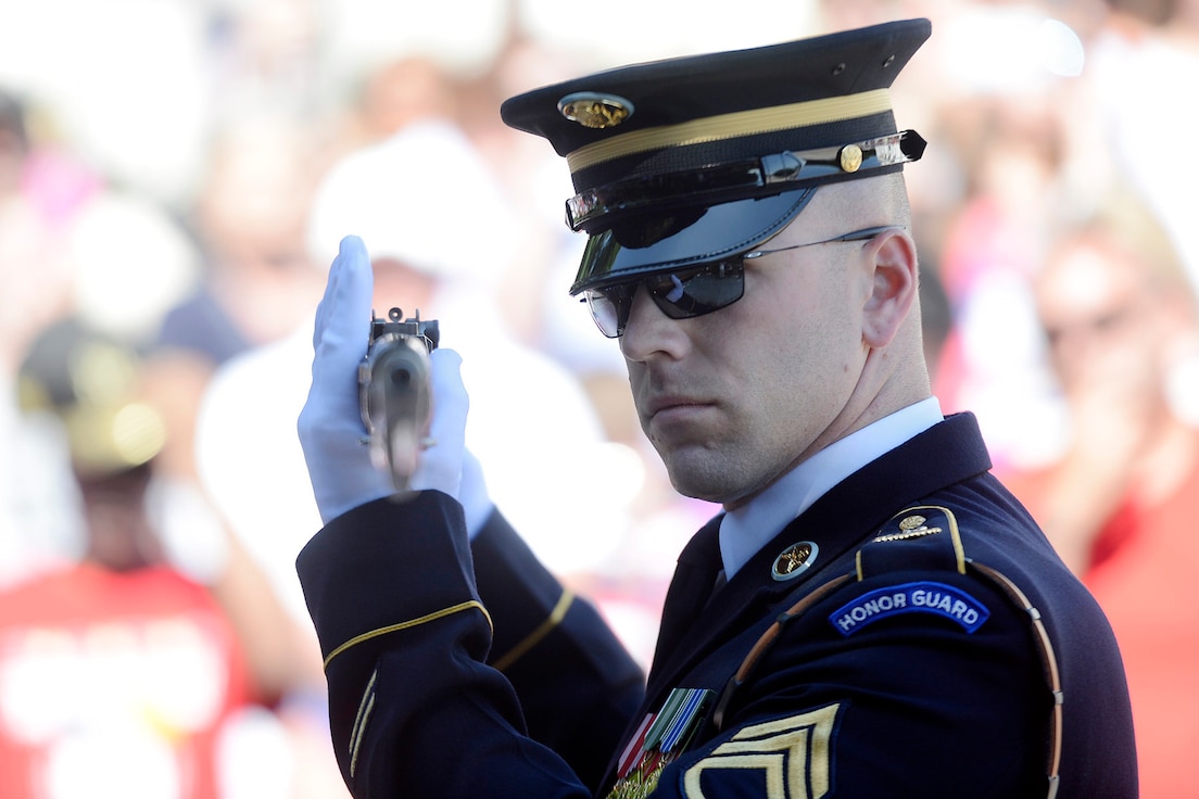 A soldier holds up a rifle to eye level during inspection.