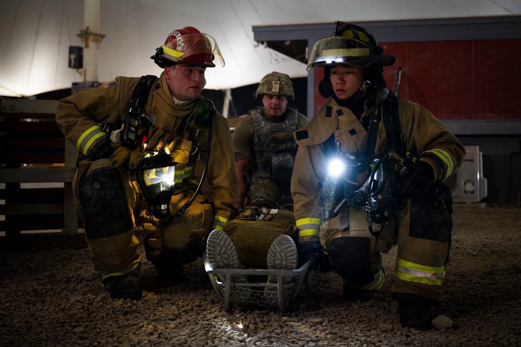 Photo of U.S. Air Force firefighters providing self-aid to a member during a training scenario